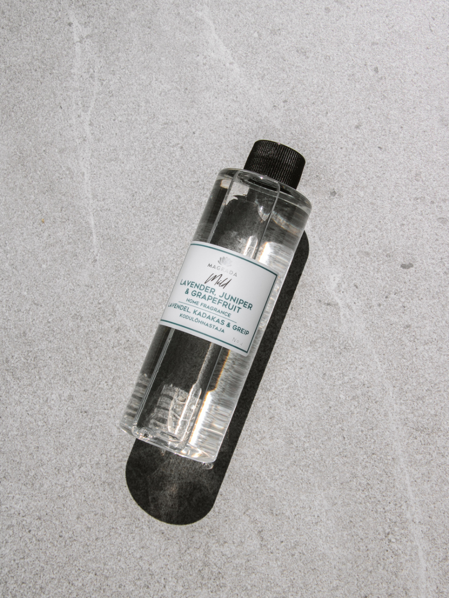 Magrada Organic Cosmetics clear bottle of juniper grapefruit room scent with black cap on gray background