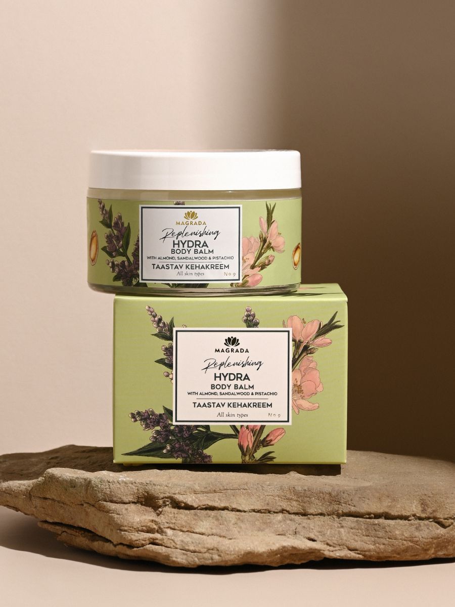 Magrada moisturizing balm Hydra body balm in green container and box with floral design on natural stone