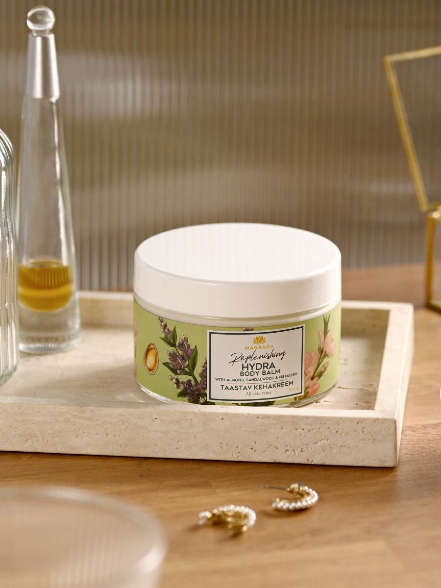 Magrada moisturizing balm in a green jar with white lid placed on a beige tray on wooden surface