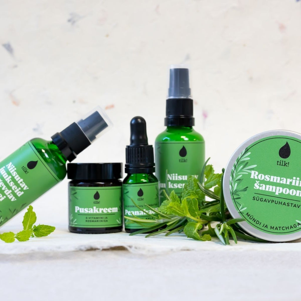 Tilk vitamin E hair detangling cream and green skincare products with fresh herbs on white background