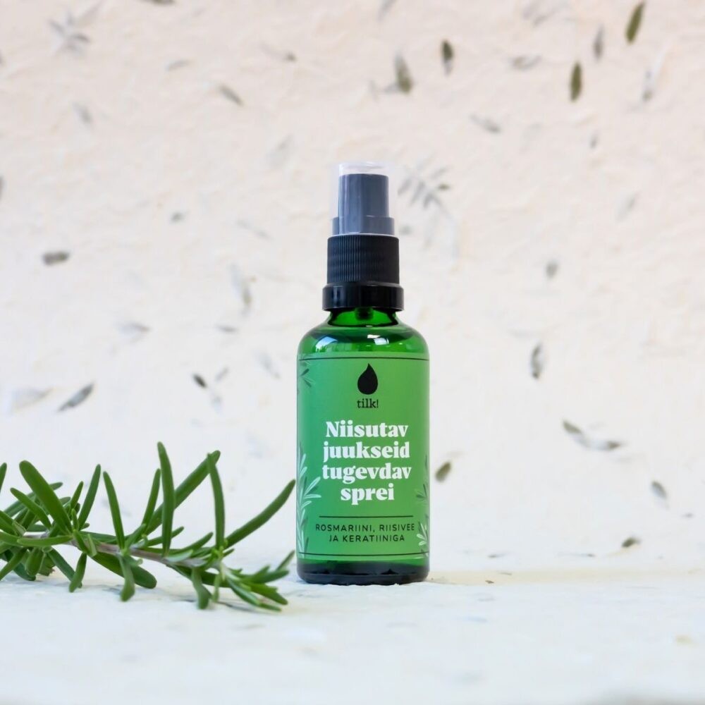 Tilk moisturizing hair spray in green bottle with spray nozzle and rosemary sprig on white surface