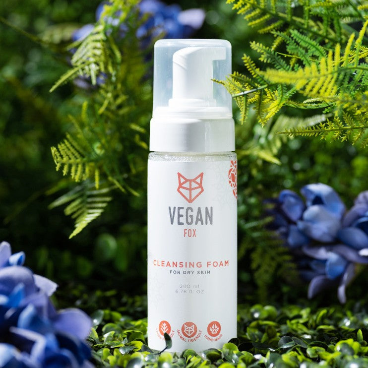 Vegan Fox vegan cleansing foam for dry skin in white bottle with pump surrounded by green plants and blue flowers