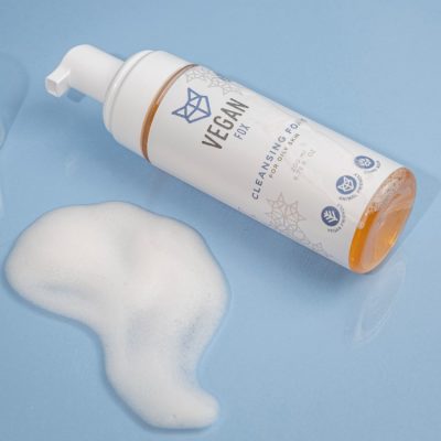 Vegan Fox vegan cleansing foam for oily skin in white pump bottle with foam on blue surface