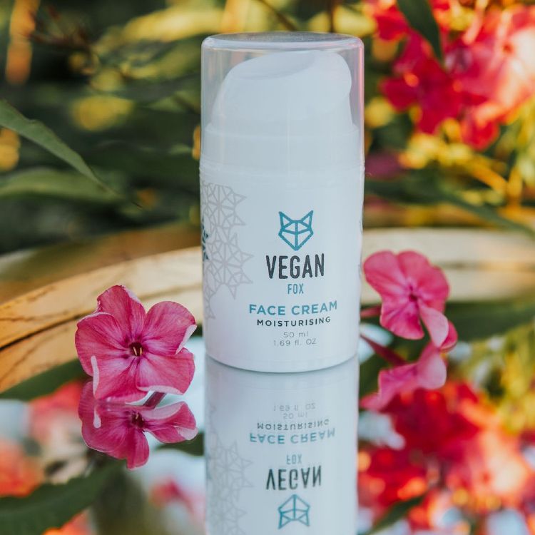 Vegan Fox vegan moisturizing face cream in a white pump bottle with pink flowers and green foliage background